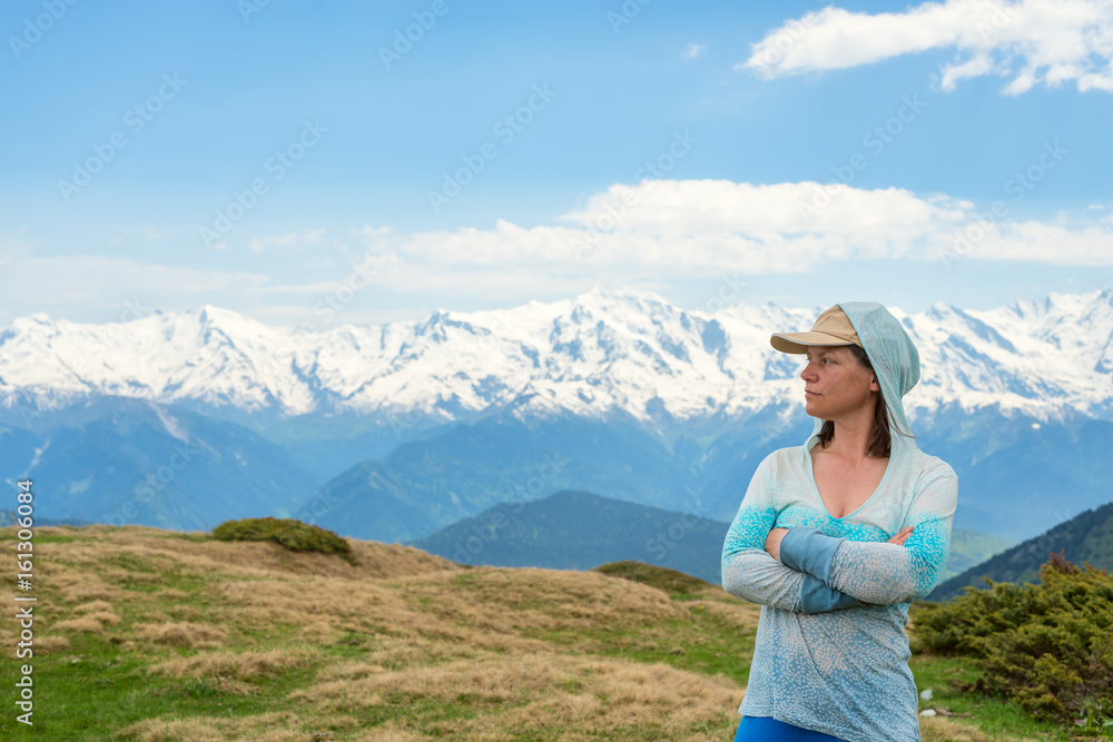 Proud woman, a traveler stands against the background of snow-covered mountain ranges