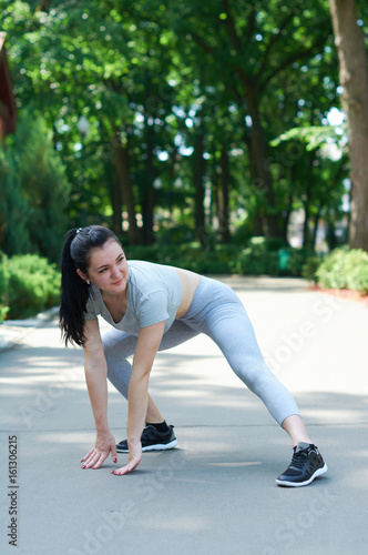 Beautiful brunette girl exercising in a green park. Training in nature. A healthy lifestyle. Sportswear.