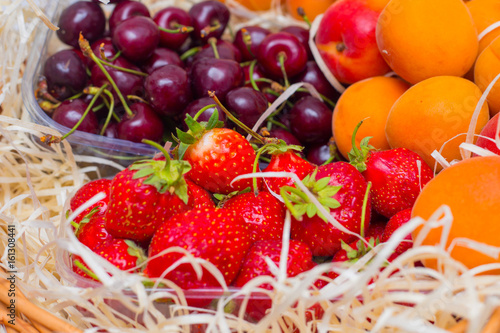 Fruits in a basket of apricots, strawberries and sweet cherries. Summer basket with vitamins
