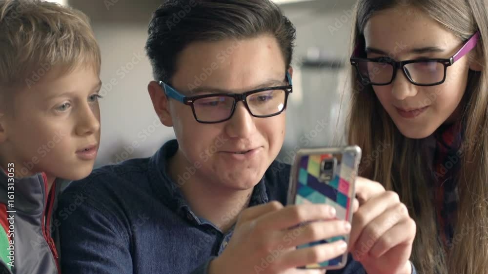 Happy children talking and browsing Internet on smartphone by table at home
Happy children talking and browsing Internet on smartphone by table at home