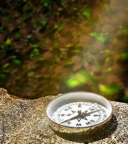 compass on small gravel stone background in sun light, changing direction for a better way concept