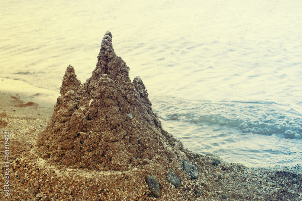 Sand castle on the beach on the seashore, toned. Rest by the sea Sand castle on the beach on the seashore, toned. Rest by the sea