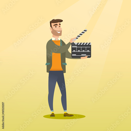 Smiling man holding an open clapperboard.