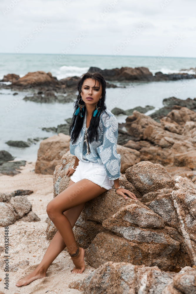 Portrait of a beautiful, amazing dreamy girl, against the sea, perfect face, brooding look, bronze skin, dark long hair, shirt, accessories, feather earrings, indie, bohemian, Bo-ho style, summer