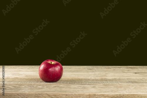 Red apple on a wooden table, black background