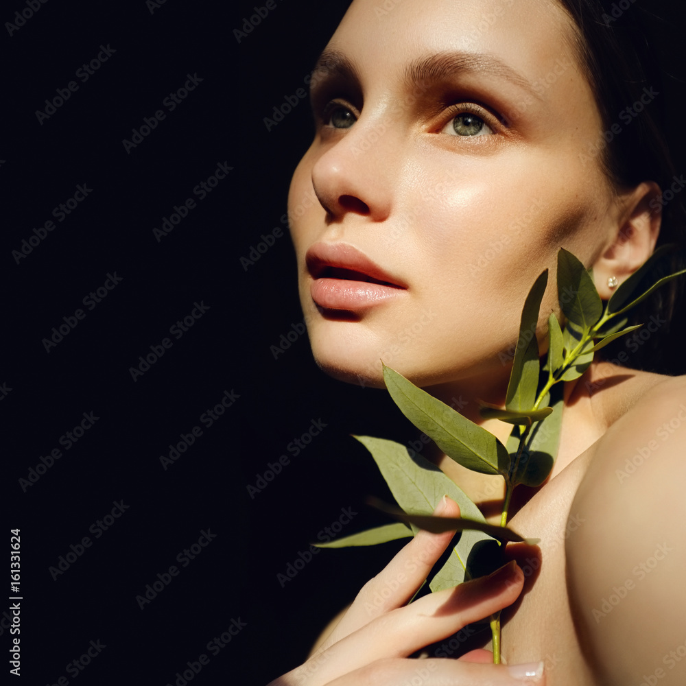 Portrait of a beautiful young brunette woman with green leaf in his hand in the studio, the concept of beauty and health Portrait of a beautiful young brunette woman with green leaf in his hand in the studio, the concept of beauty and health
