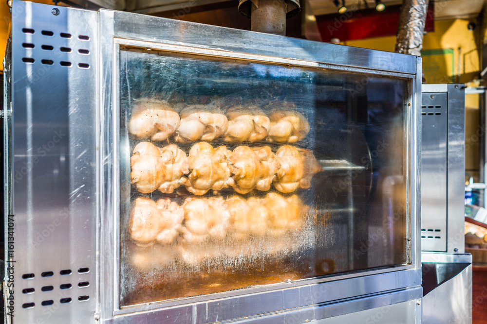 Rotisserie chicken machine with many plump birds roasting