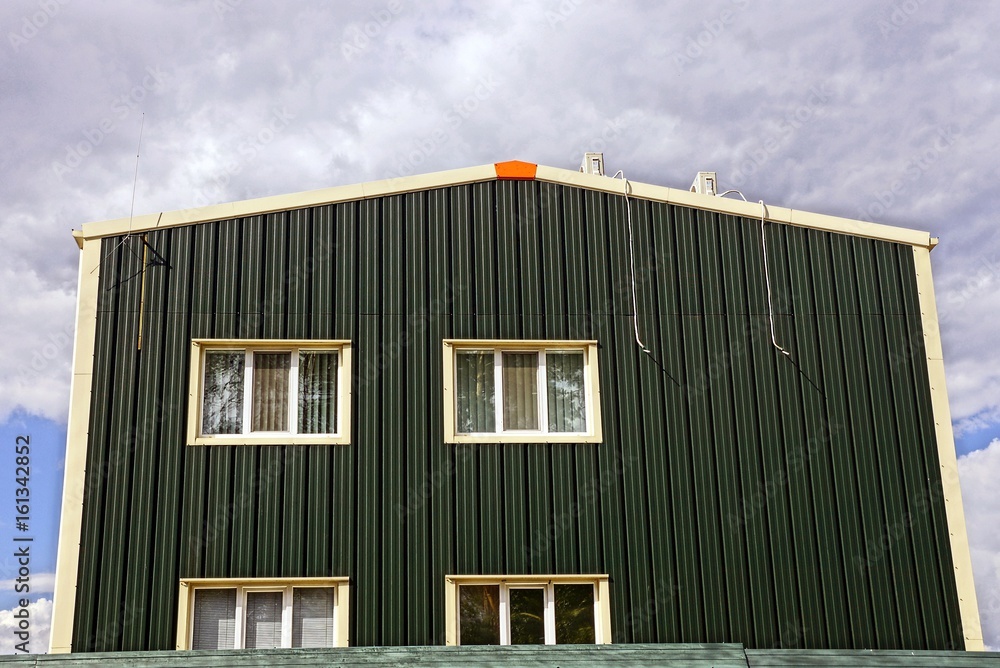 зелёный фасад частного здания с окнами 