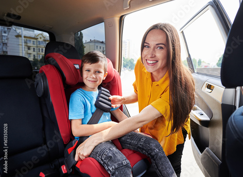 Graceful mom checking son sitting in baby seat