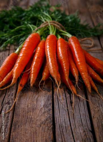 Bunch of fresh carrots with green leaves over wooden background. Vegetable.Food or Healthy diet concept.Vegetarian.Copy space for Text. selective focus.