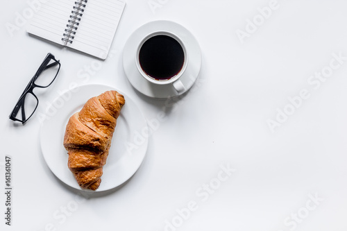Businessman morning with notebook, cup of coffee and croissant on wooden table background top view mockup