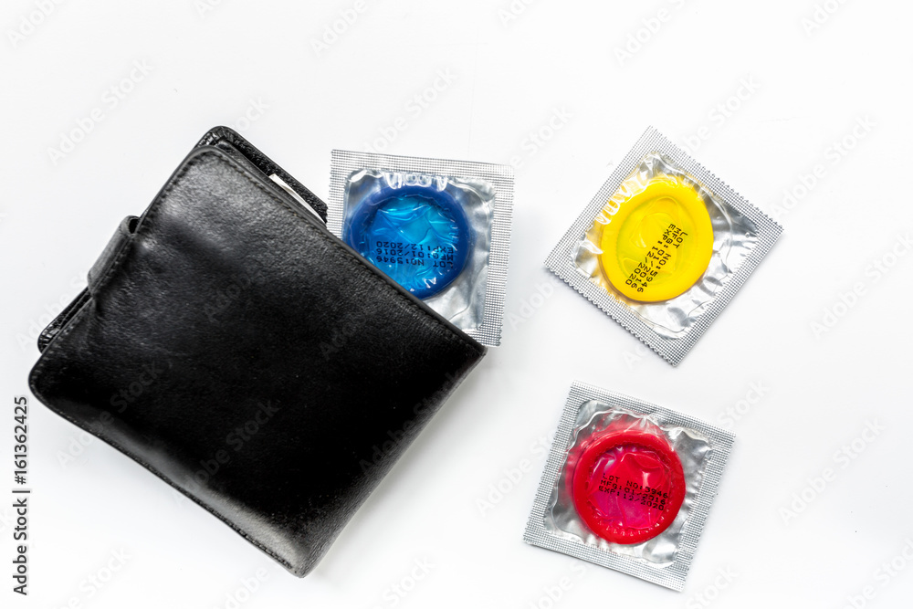 Obraz premium male contraception with condom and wallet on white background top view