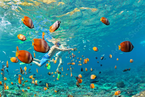 Canvas Print Happy family - couple in snorkeling masks dive deep underwater with tropical fishes in coral reef sea pool