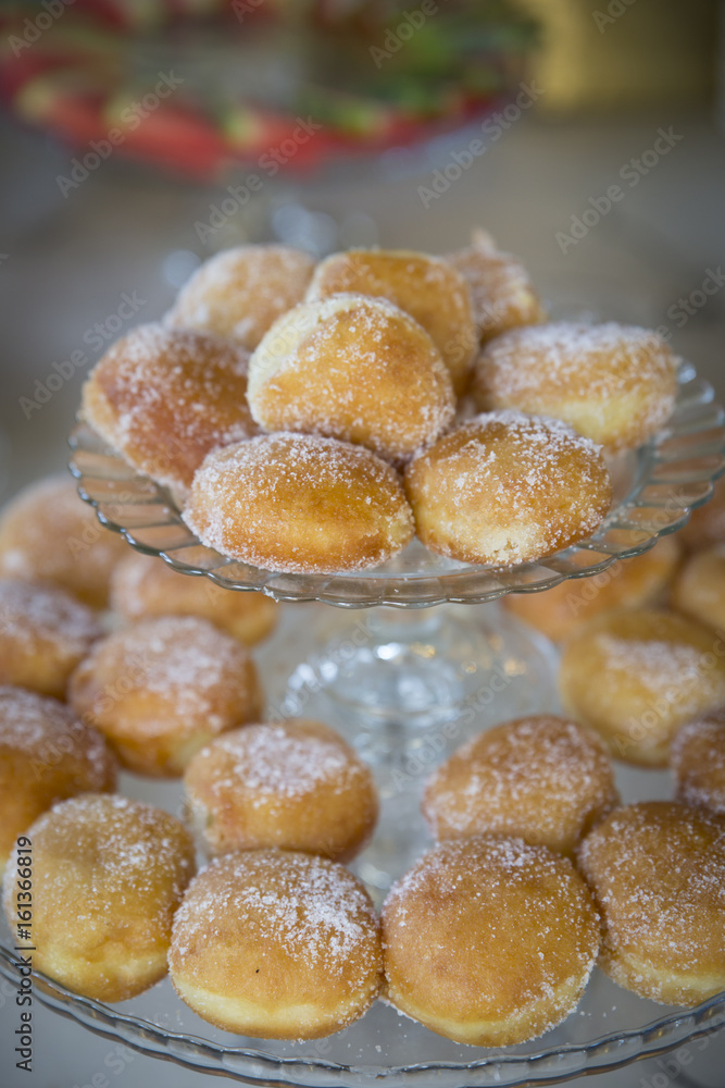 Donuts with icing sugar on baking pan heating in a wedding reception