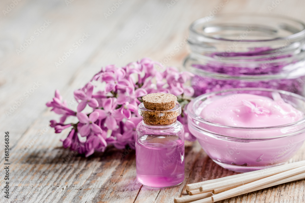 organic salt, cream, extract in lilac cosmetic set with flowers on wooden table background organic salt, cream, extract in lilac cosmetic set with flowers on wooden table background