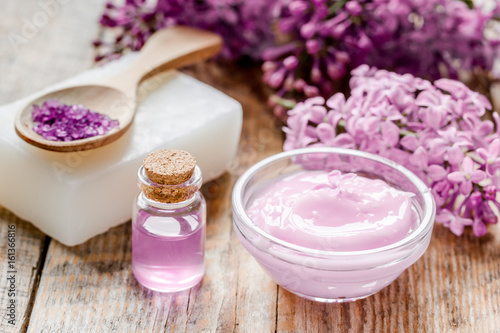 lilac cosmetics with flowers and spa set on wooden table background
