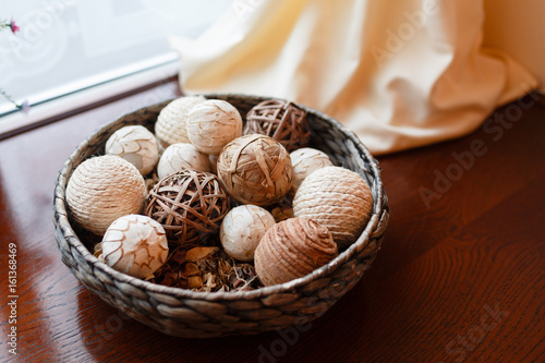 Wicker bowl with wicker balls. Decorative object asian wooden wicker spheres lay in wooden bowl