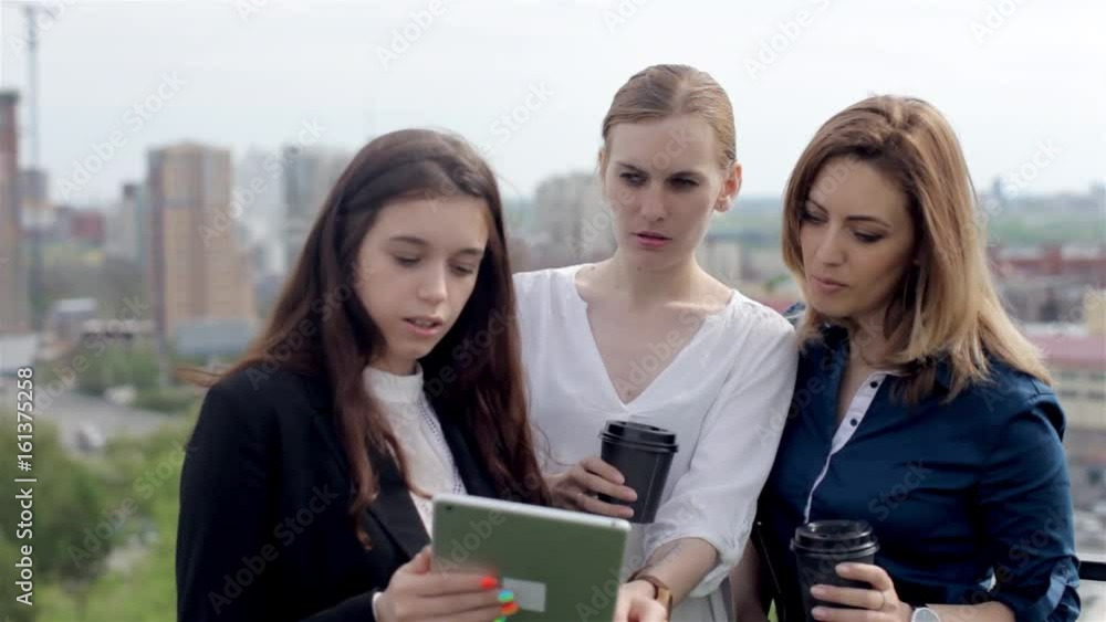 Business Conference on The Roof. Three Business Women Discuss Working With a Tablet on the Roof Overlooking the City Business Conference on The Roof. Three Business Women Discuss Working With a Tablet on the Roof Overlooking the City