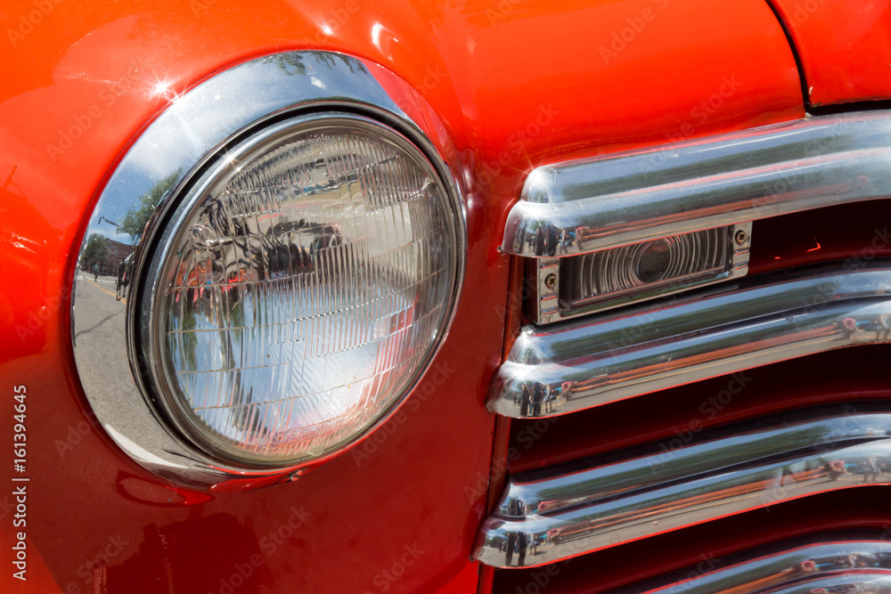 Headlight and chrome grille on an orange classic car