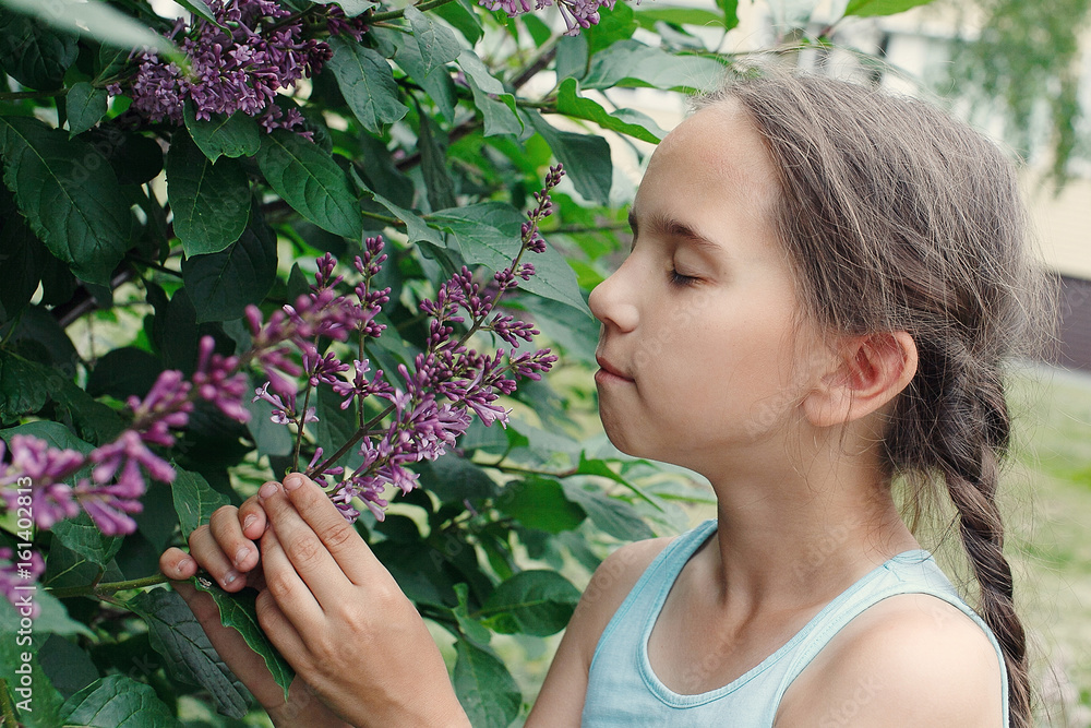 Beautiful little girl smelling lilac flowers in the summer Beautiful little girl smelling lilac flowers in the summer