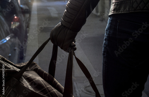 Tableau sur toile Terrorist standing in dark alley in the city center holding black bomb back with leather gloves