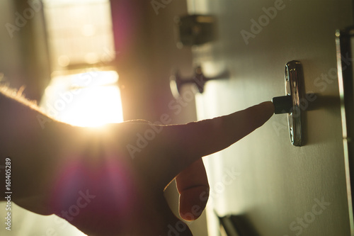 Finger pressing doorbell in sunny apartment building corridor Fototapeta