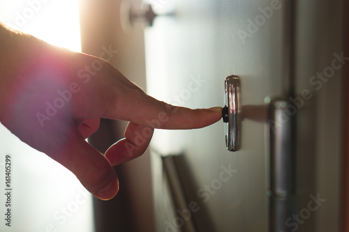 Fotografija Finger pressing doorbell in sunny apartment building corridor