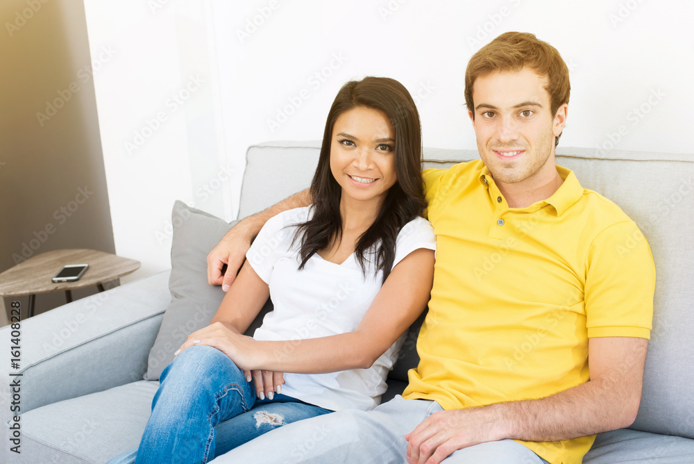 Young mixed race couple sitting on the couch in living room Young mixed race couple sitting on the couch in living room