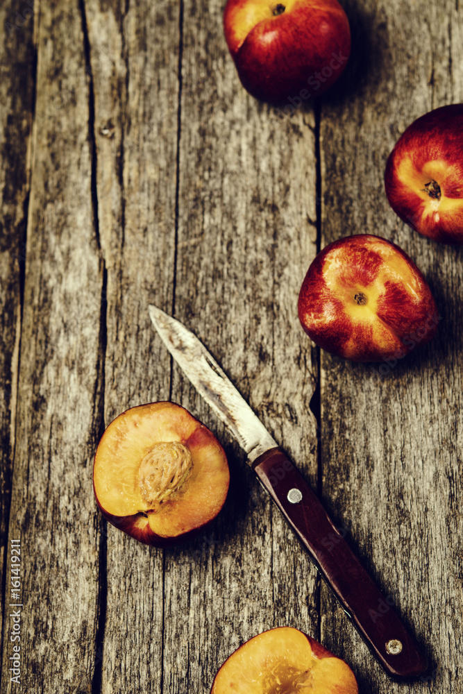 Ripe juicy peaches whole and slices and knife on old rustic wooden table. Selective focus. Toned image Ripe juicy peaches whole and slices and knife on old rustic wooden table. Selective focus. Toned image