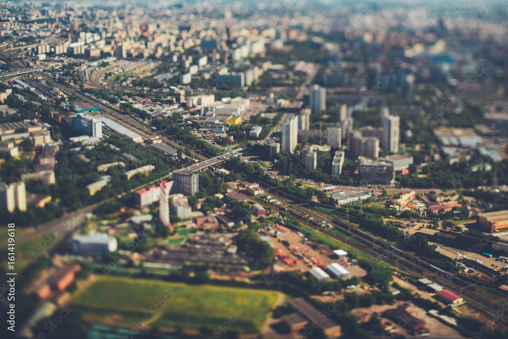 True tilt-shift view from very high above of railway with several tracks, aerial view of railroad station in focus surrounded by defocused residential districts and industrial zone, Moscow, Russia