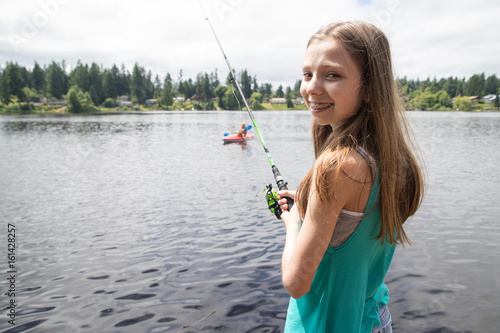 Cute young girl with braces fishing on a lake