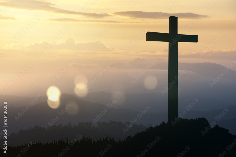 Concept conceptual black cross religion symbol silhouette in grass over sunset or sunrise sky