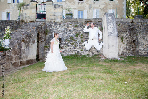 bride and groom jump in park for fun photo