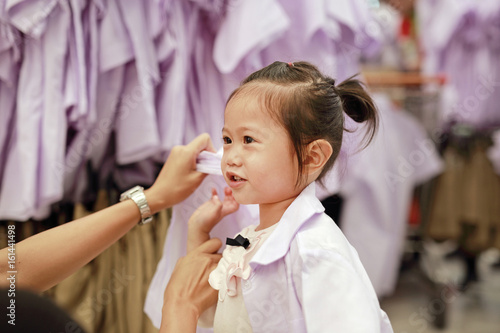 Mother try dressing school uniform for her daughter, Kindergarten children. photo