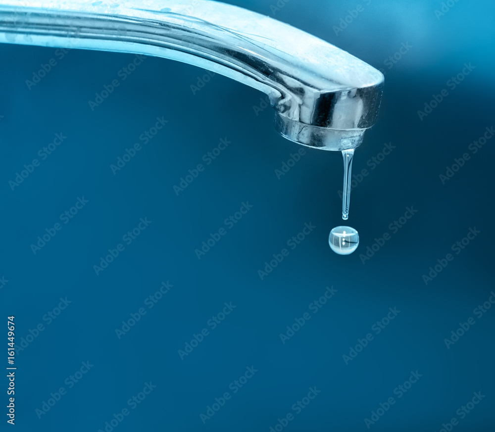 Water droplets drip flowing from chrome faucet on a blue background. Of the idea of saving water. Water droplets drip flowing from chrome faucet on a blue background. Of the idea of saving water.