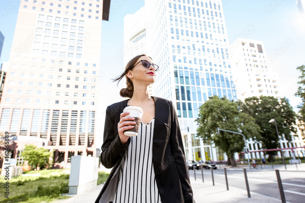 Businesswoman walking with cup of coffee in the park of the modern district in Frankfurt city Businesswoman walking with cup of coffee in the park of the modern district in Frankfurt city