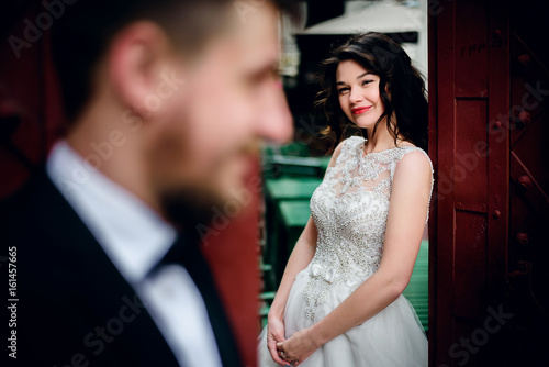Bride looks at groom from behind red gates