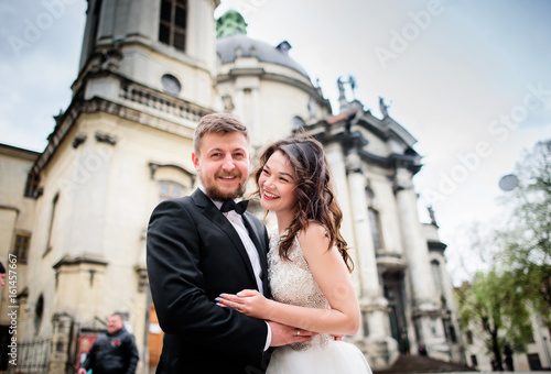 Wedding couple smiles posing before an old church © IVASHstudio
