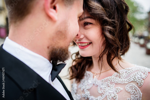 Smiling brunette bride looks in groom's eyes