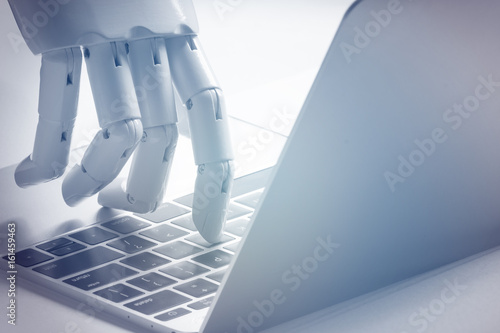 Chat bot , artificial intelligence , robo advisor , robotic concept. Robot finger point to laptop button. Blue tone. photo