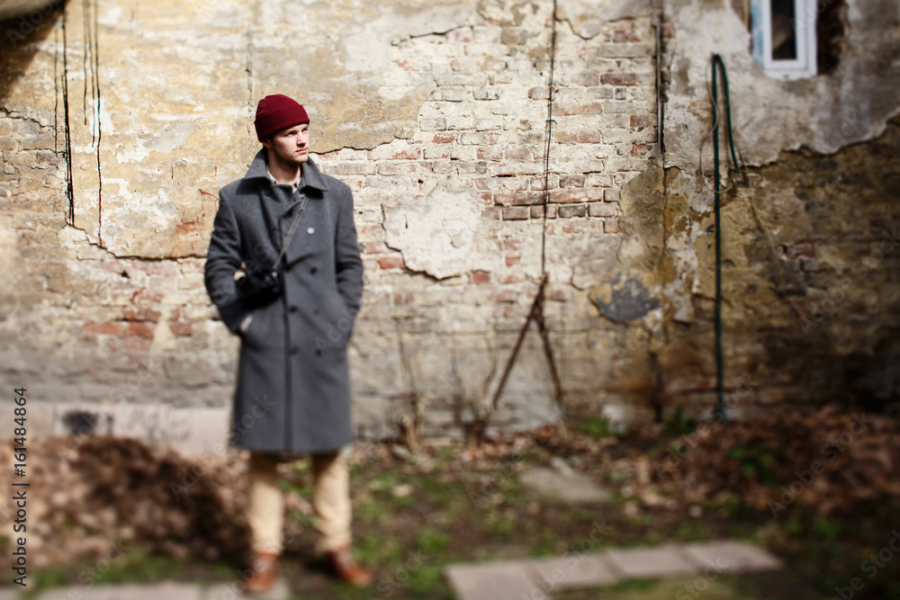 Blurred picture of man in grey coat standing before ruined wall Blurred picture of man in grey coat standing before ruined wall