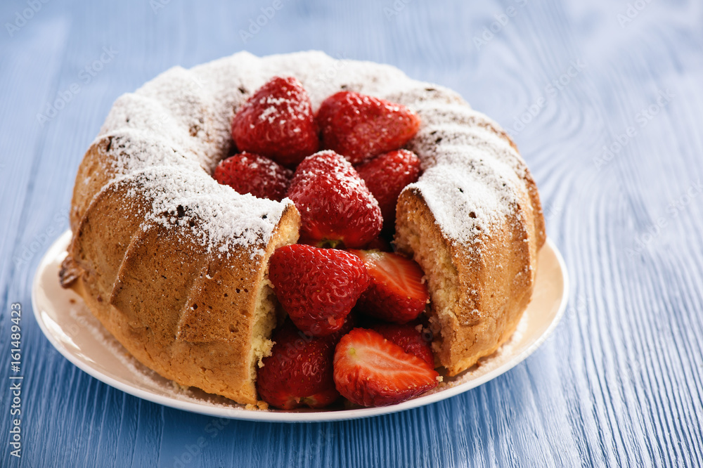 Homemade cake with strawberries on wooden background.