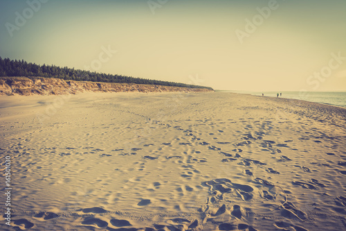 Empty beach with white sand near dunes over sea  summer landscape in Poland  photo stylized on vintage