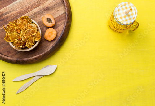 Blank yellow tabletop scene with zucchini chips and apricots