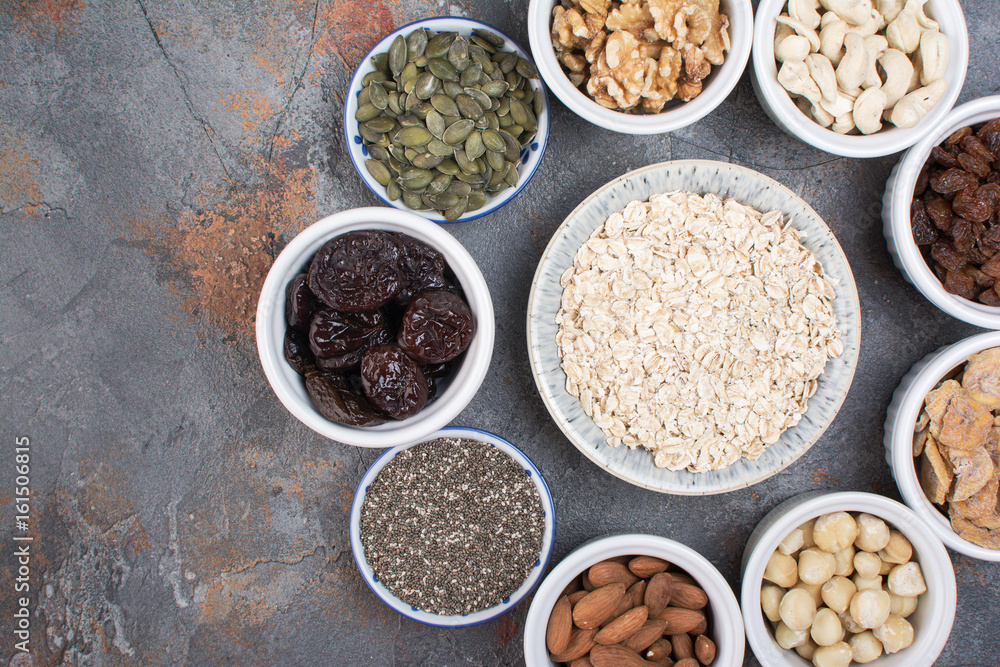Ingredients for homemIngredients for homemade granola, oats, different nuts and raisins, dates, seed on the grey stone background, top viewade granola on the grey Ingredients for homemIngredients for homemade granola, oats, different nuts and raisins, dates, seed on the grey stone background, top viewade granola on the grey