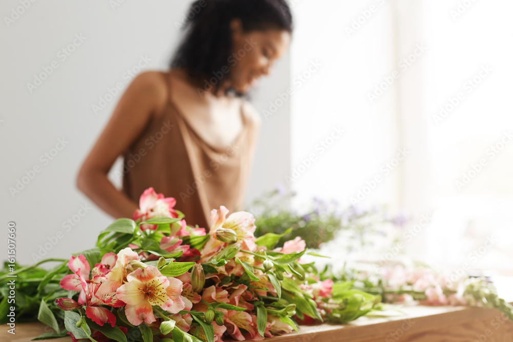 Beautiful african female florist working background. Focus on alstroemerias. Beautiful african female florist working background. Focus on alstroemerias.