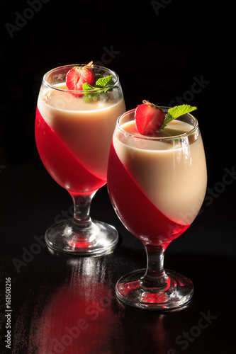 Cherry and milk jelly in the glasses topped mint leaves and strawberry pieces