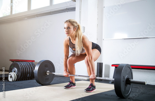 Woman doing deadlift exercise, weight lifting workout at crossfit gym