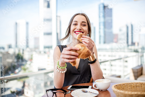 Young businesswoman having a breakfast outdoors with beautiful cityscape view at the modern district in Frankfurt