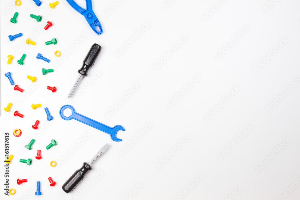 Colorful kids toys border. Plastic toy tools, bolts and nuts on white background. Top view